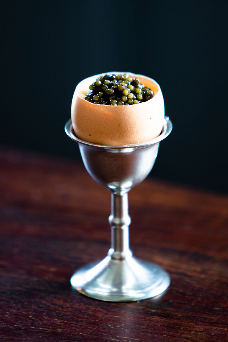 caviar in an egg shell that has been hollowed out and placed in an egg stand