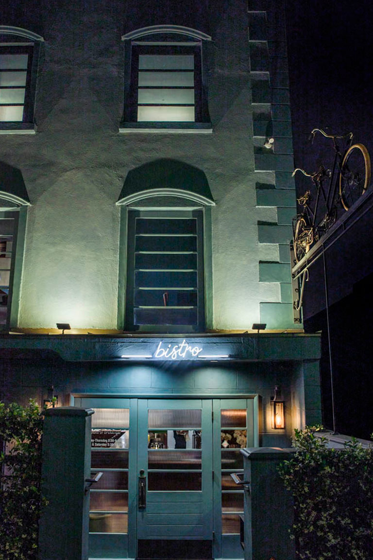 exterior of the bistro entrance, with lit neon sign that says bistro